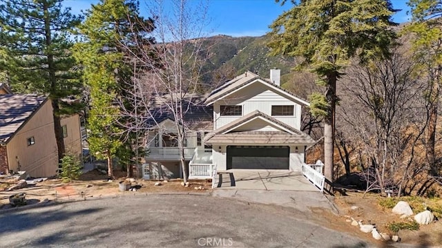 view of front facade featuring a garage, concrete driveway, and a chimney