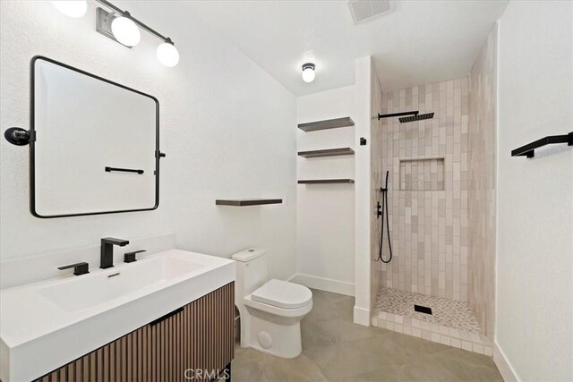 full bathroom with toilet, visible vents, tiled shower, and vanity