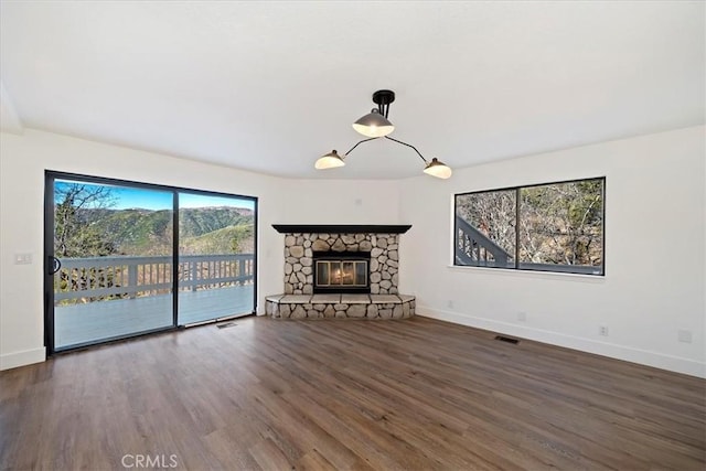 unfurnished living room with a fireplace, wood finished floors, visible vents, and baseboards