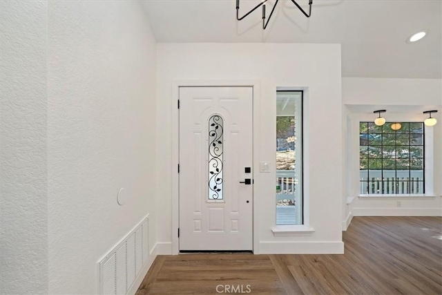 foyer entrance featuring baseboards, visible vents, wood finished floors, and recessed lighting