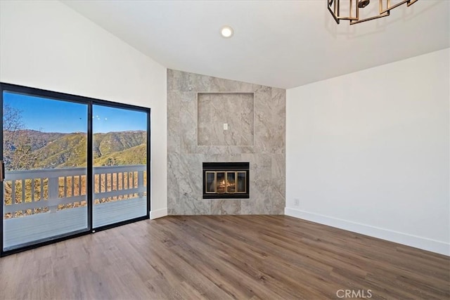 unfurnished living room with recessed lighting, lofted ceiling, wood finished floors, a tile fireplace, and baseboards