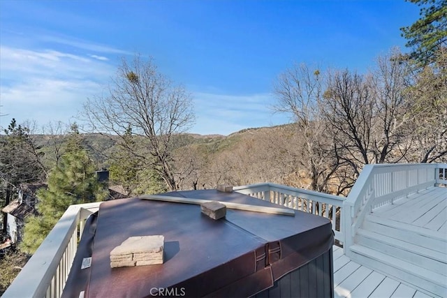 deck with a hot tub and a view of trees