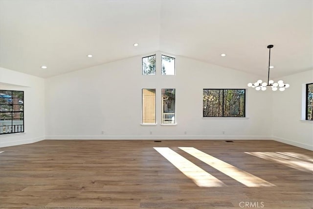 empty room featuring a chandelier, a healthy amount of sunlight, baseboards, and wood finished floors