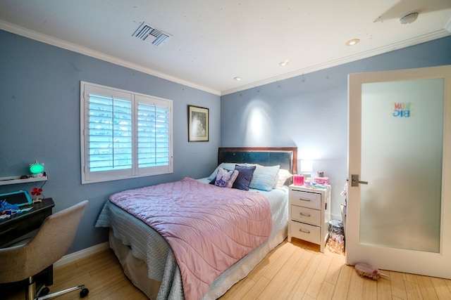 bedroom featuring baseboards, wood finished floors, visible vents, and crown molding