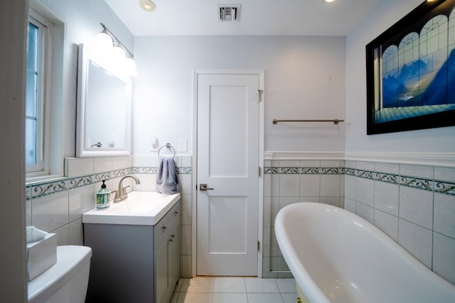 bathroom featuring tile patterned flooring, toilet, vanity, visible vents, and a soaking tub