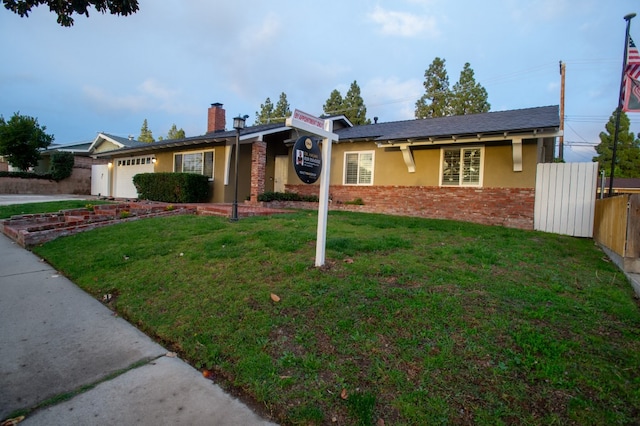 ranch-style house with brick siding, fence, a front lawn, and stucco siding