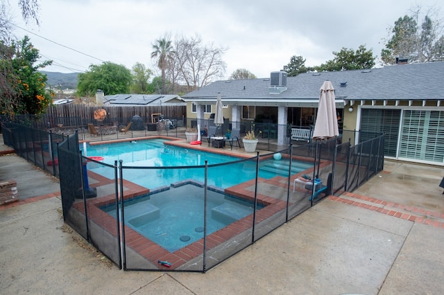 view of swimming pool with a pool with connected hot tub, a patio area, and fence