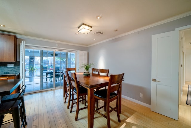 dining room with ornamental molding, light wood-style flooring, visible vents, and baseboards