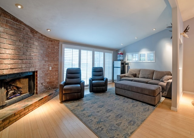 living area with a brick fireplace, vaulted ceiling, baseboards, and wood finished floors