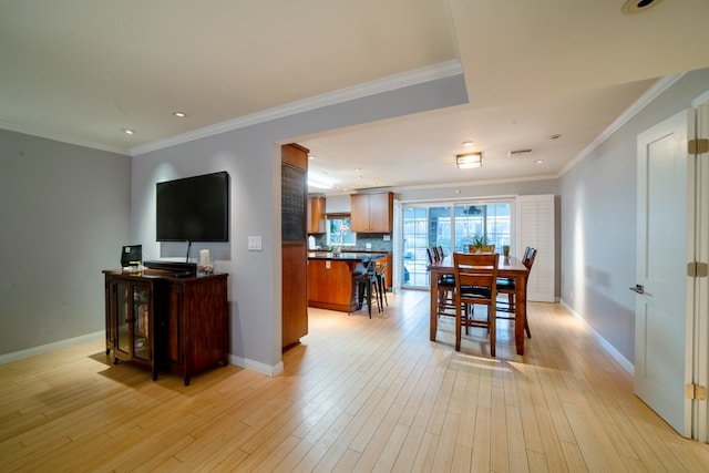 dining space with light wood-style floors, baseboards, and ornamental molding