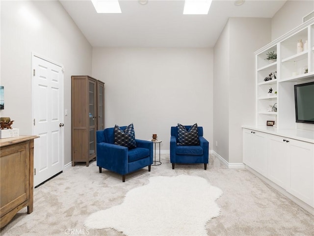 sitting room featuring light carpet, a skylight, and baseboards