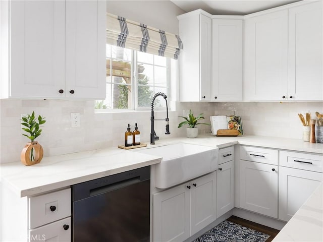 kitchen with black dishwasher, light countertops, backsplash, white cabinetry, and a sink