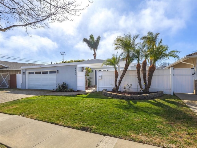 view of front facade with decorative driveway, stucco siding, a front yard, a gate, and fence