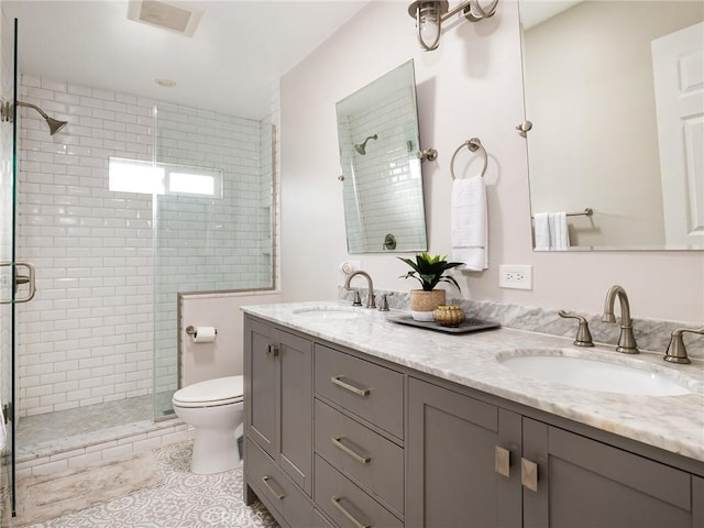 full bathroom with double vanity, a shower stall, toilet, and a sink