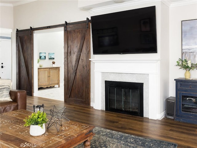 living area with dark wood-style floors, a barn door, ornamental molding, and a tile fireplace