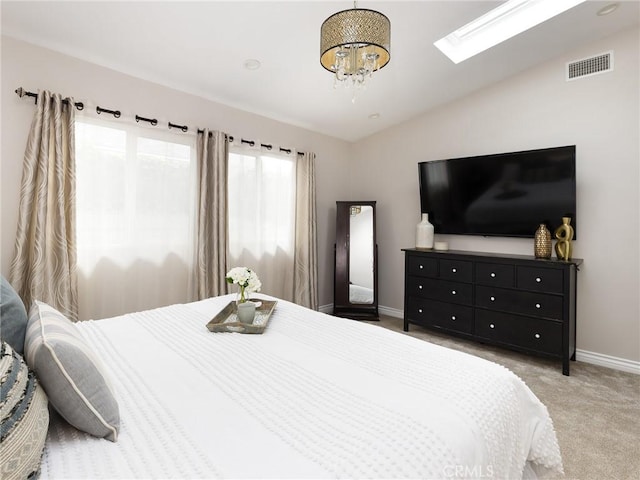 bedroom with light carpet, vaulted ceiling with skylight, visible vents, baseboards, and a chandelier