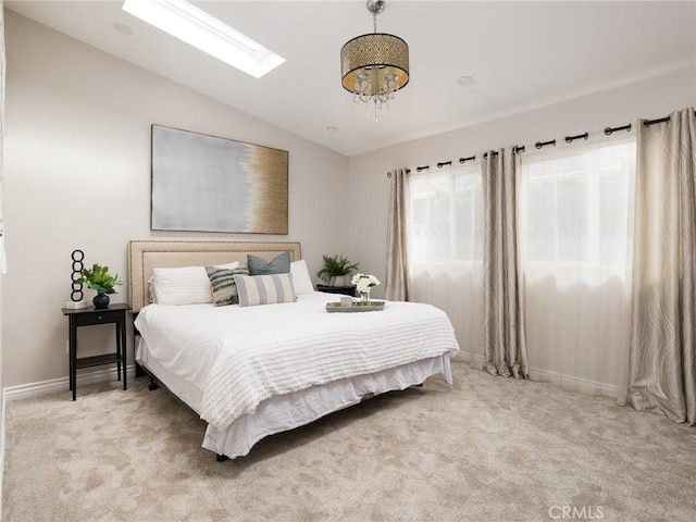 bedroom featuring lofted ceiling with skylight, baseboards, and light colored carpet