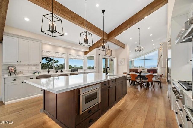 kitchen with light countertops, light wood finished floors, beamed ceiling, and a sink