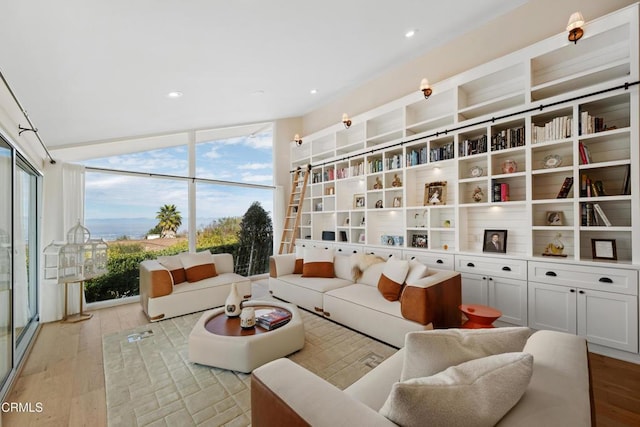 living area with vaulted ceiling, light wood finished floors, recessed lighting, and floor to ceiling windows