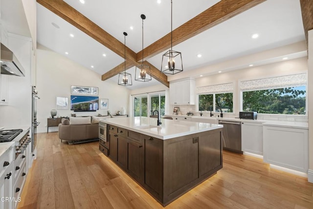 kitchen with appliances with stainless steel finishes, light wood-style floors, open floor plan, white cabinetry, and dark brown cabinetry