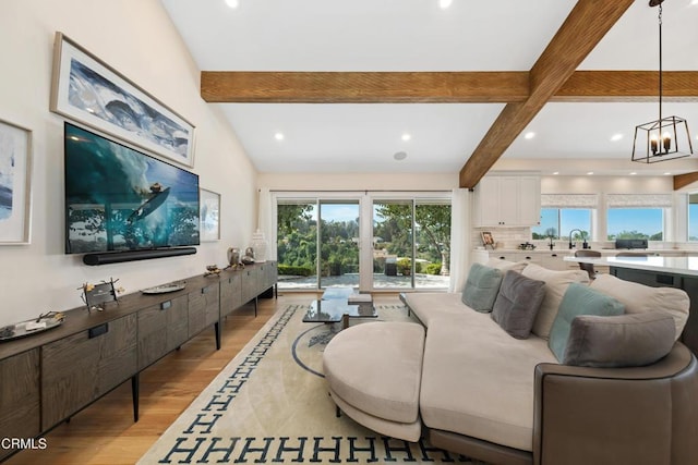 living area with recessed lighting, a notable chandelier, lofted ceiling with beams, and light wood finished floors