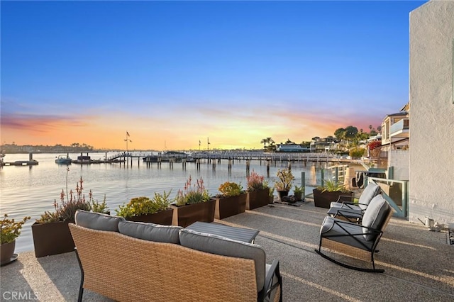 patio terrace at dusk with outdoor lounge area and a water view