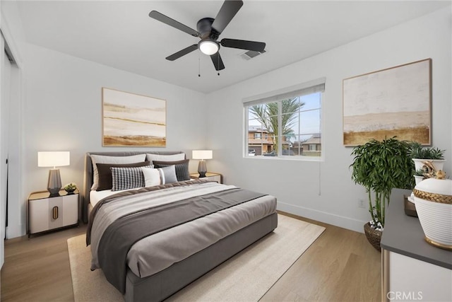 bedroom with visible vents, light wood-type flooring, a ceiling fan, and baseboards