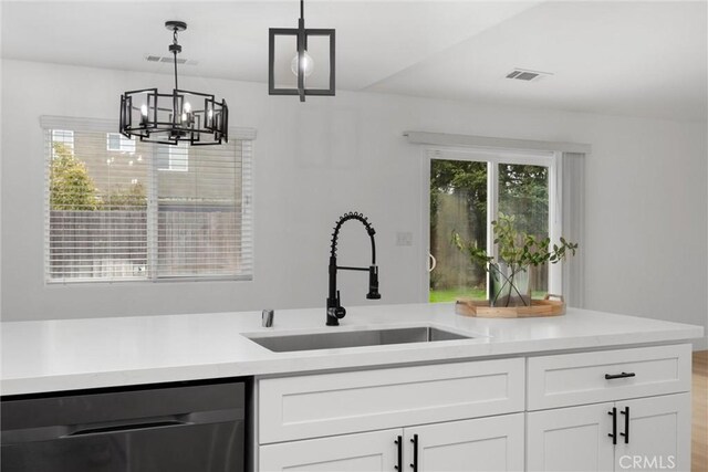 kitchen featuring pendant lighting, light countertops, dishwasher, and a sink