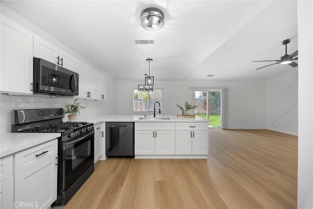 kitchen with light countertops, visible vents, white cabinetry, a sink, and black appliances