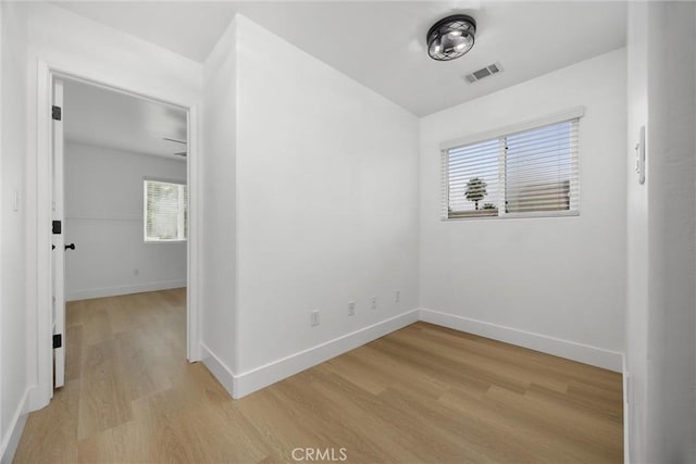 unfurnished room with light wood-type flooring, visible vents, and baseboards