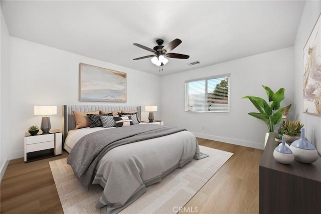 bedroom with wood finished floors, visible vents, and baseboards