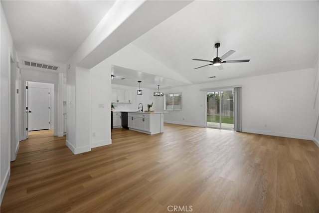 unfurnished living room featuring visible vents, light wood-style flooring, a ceiling fan, a sink, and baseboards