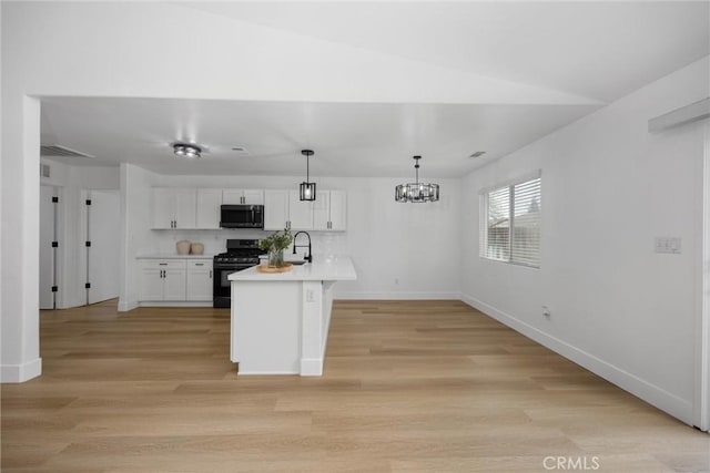 kitchen featuring light countertops, stainless steel microwave, hanging light fixtures, white cabinetry, and gas range