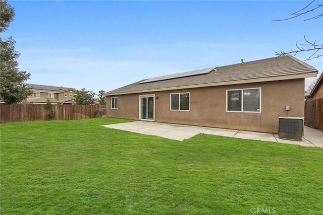 back of property with solar panels, a lawn, and a fenced backyard