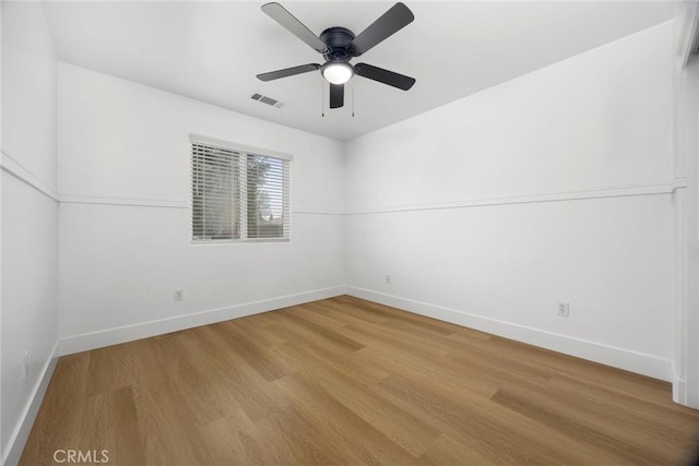 unfurnished room with baseboards, visible vents, ceiling fan, and wood finished floors