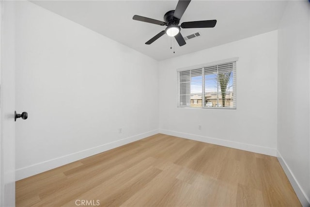 spare room featuring light wood finished floors, baseboards, visible vents, and ceiling fan