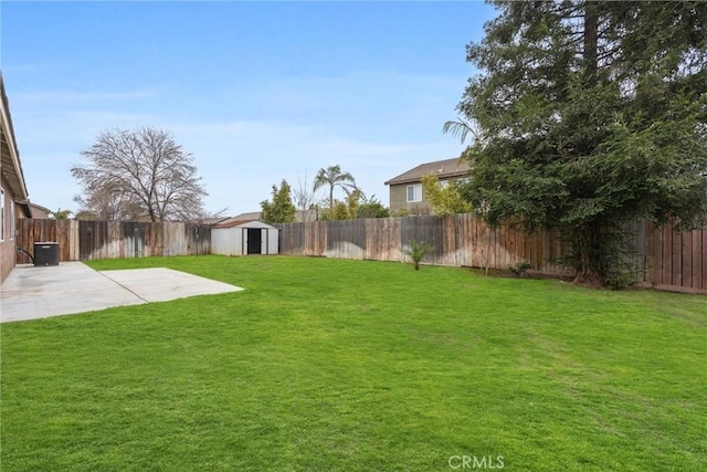 view of yard with an outbuilding, a patio, a storage unit, cooling unit, and a fenced backyard