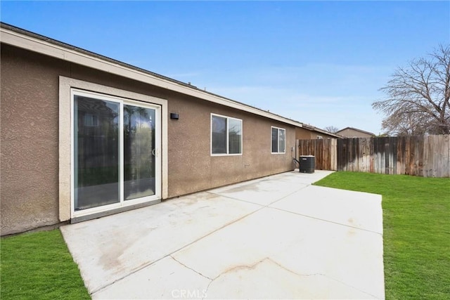 back of property featuring a patio, fence, a yard, central AC, and stucco siding