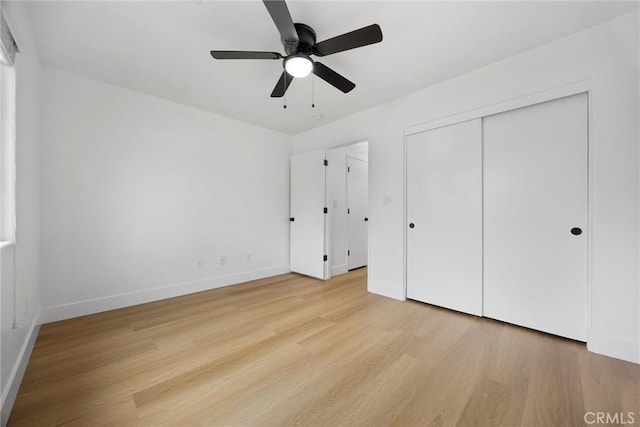 unfurnished bedroom with light wood-type flooring, a closet, ceiling fan, and baseboards