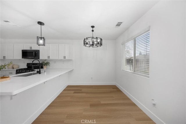 kitchen with visible vents, white cabinets, light countertops, black range oven, and stainless steel microwave