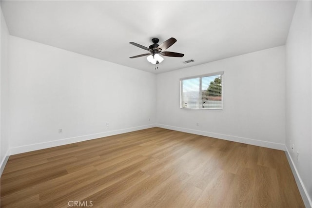 unfurnished room with ceiling fan, visible vents, light wood-style flooring, and baseboards