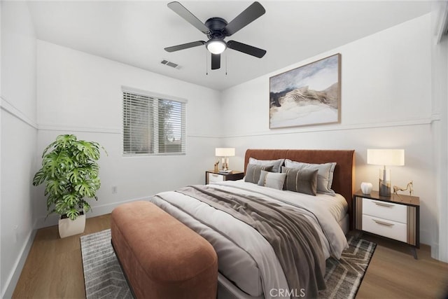 bedroom with dark wood-type flooring, a ceiling fan, visible vents, and baseboards