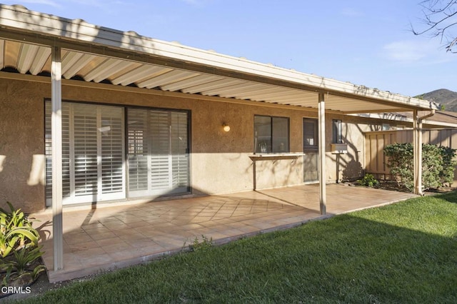 back of property with a yard, a patio, and stucco siding