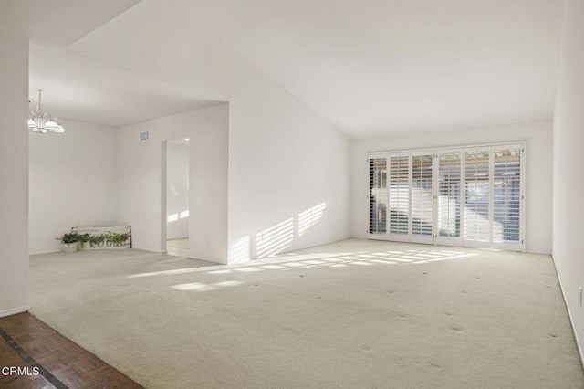 spare room with carpet flooring, vaulted ceiling, visible vents, and an inviting chandelier