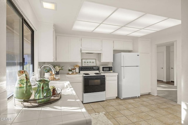 kitchen with white appliances, white cabinets, a sink, and under cabinet range hood