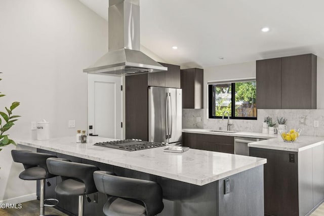 kitchen with stainless steel appliances, a sink, dark brown cabinets, decorative backsplash, and island exhaust hood