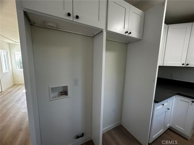 laundry area with hookup for a washing machine, baseboards, dark wood finished floors, and cabinet space