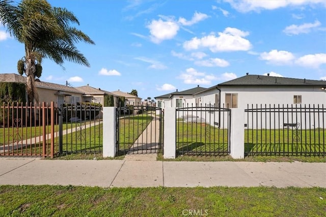 view of gate with a fenced front yard, a residential view, and a lawn