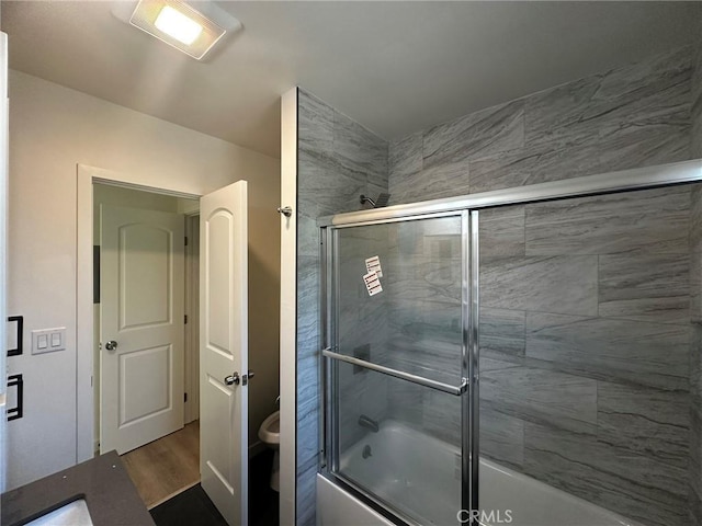 full bathroom featuring toilet, enclosed tub / shower combo, and wood finished floors