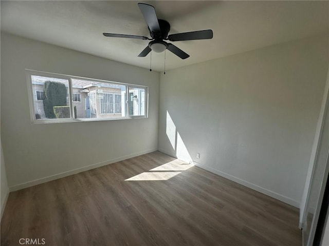 empty room featuring a ceiling fan, baseboards, and wood finished floors